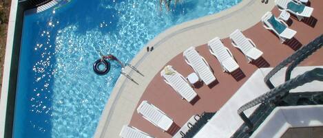 Una piscina al aire libre de temporada, sombrillas