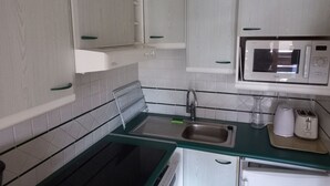 A kitchen with white cabinets, a microwave, a sink, and a stove. - Studio with balcony and wifi 500m from slopes (Tignes)