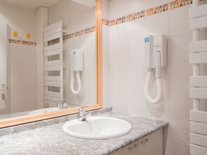 Un baño con lavamanos blanco, un espejo y un perchero para toallas.