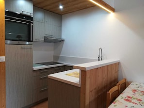 A compact kitchen with a microwave, stove, and sink.