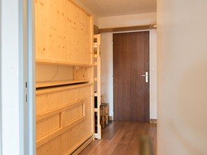 A hallway with a wooden wardrobe, a wooden door, and a trash bin. - South-facing studio 500 m from slopes with Wi-Fi (Tignes)