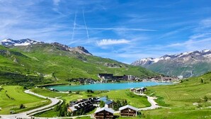 A mountainous landscape with a lake, a winding road, and buildings with a modern design.