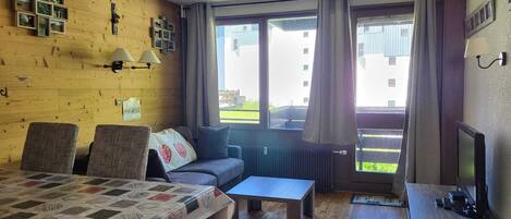 Een gezellige kamer met een houten wand, een bank, een tafel en een televisie.