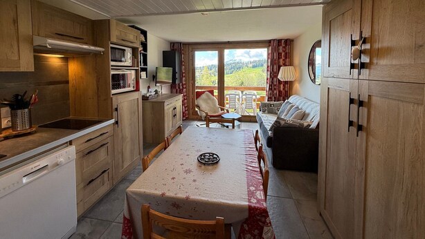 Una cocina acogedora con armarios de madera, una mesa de comedor y vistas a un paisaje pintoresco a través de un amplio ventanal.