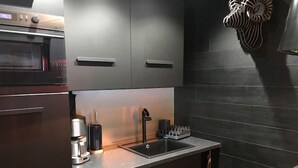 Una cocina moderna con electrodomésticos de acero inoxidable, una encimera negra y armarios oscuros.