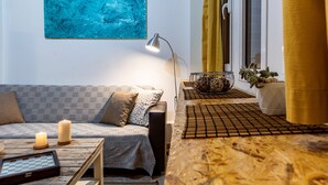 A modern living room with a sofa, two candles, a floor lamp, a coffee table, and a large abstract painting.