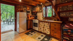 A rustic kitchen with a stone wall, wooden beams, a refrigerator, stove, and a sink. - Escape in the Forest, Cosy Chalet with Home Cinema (Kalamata)