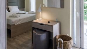 Una habitación de hotel moderna con cama, mesita de noche, lámpara y un ventanal grande.