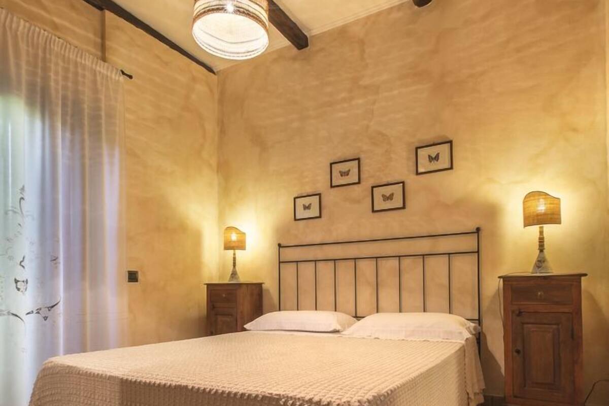 A bedroom with a large bed, wooden headboard, two bedside tables with lamps, and a ceiling light fixture.