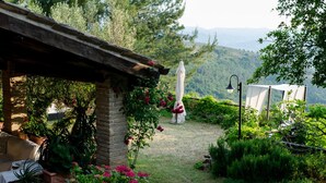 Un espacio de estar al aire libre de estilo rústico, con un muro de piedra, plantas en macetas y vistas a un paisaje montañoso.