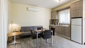 A modern kitchen with a dining table and chairs, a sofa, and a refrigerator. - Sun, Sand & Seclusion - Artemis with Private Pool (Pylos-Nestoras)