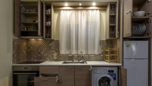 Una cocina compacta con horno integrado, lavadora y fregadero.