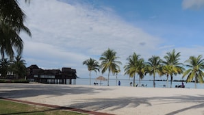 Una spiaggia con palme, una struttura in legno e un cielo sereno.