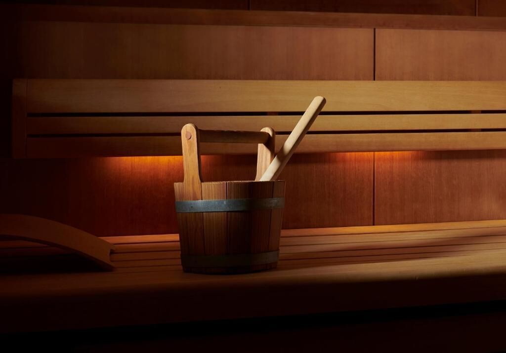 A wooden bench with a metal bucket containing a wooden spoon and spatula.