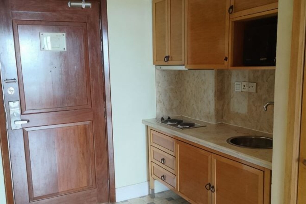 Una cocina con armarios de madera, una encimera, un lavabo y una puerta con pomo.