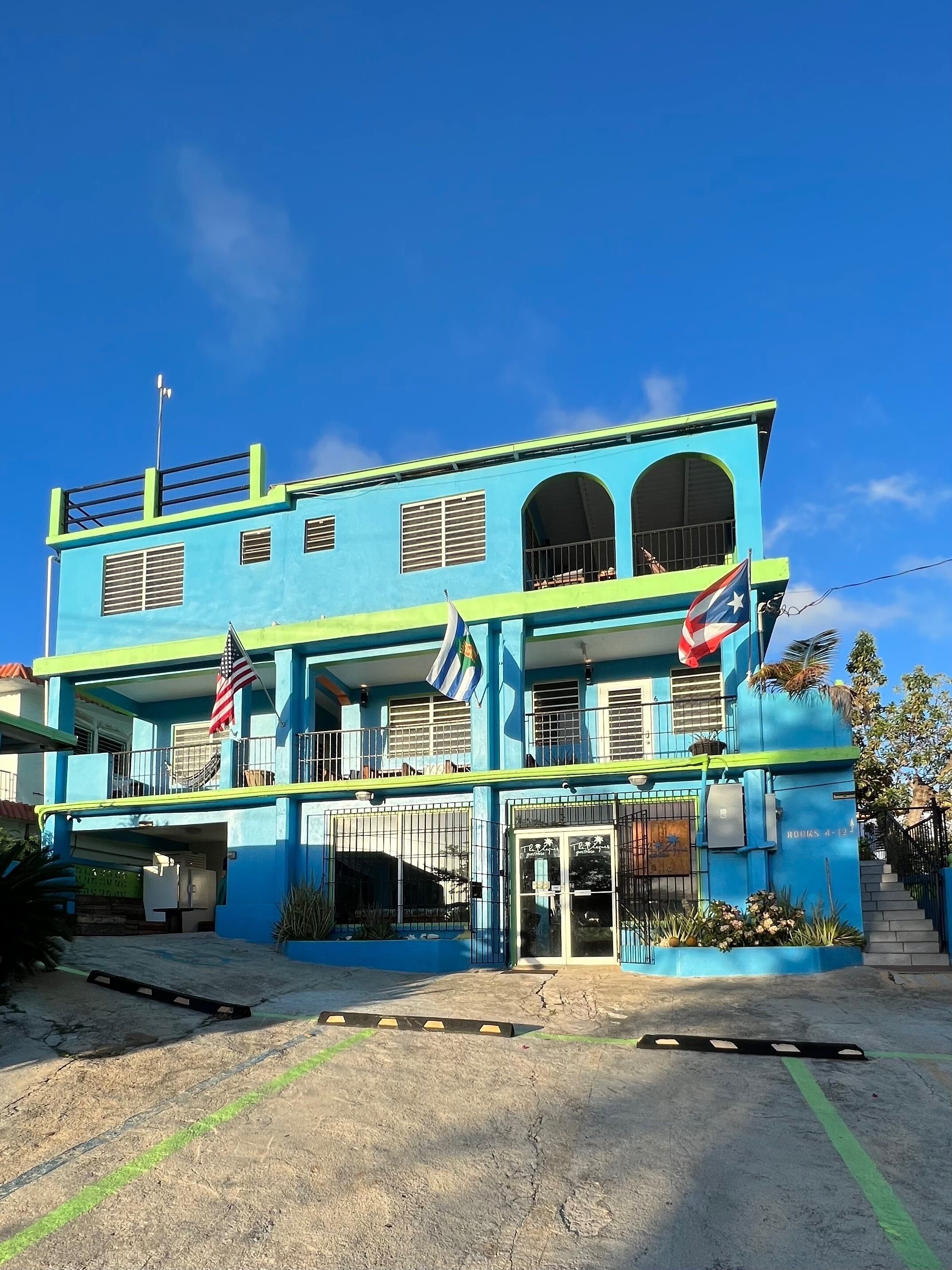 Um edifício de dois andares com fachada azul, várias janelas e bandeiras.