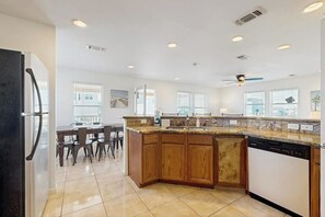 A kitchen with wooden cabinets, a dishwasher, and a dining area with chairs.