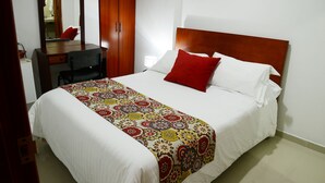 Una habitación de hotel con una cama grande, un armario de madera, un escritorio con silla y un espejo.