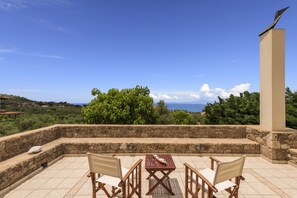 A terrace with stone walls, a table, and two chairs.