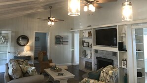 Sala de estar com lareira, ventiladores de teto e luminárias pendentes.
