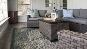Uma sala de estar aconchegante com um sofá seccional cinza, uma mesinha lateral e um candeeiro decorativo.