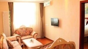 Una habitación con un sofá, una mesita y un televisor de pantalla plana montado en la pared.