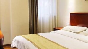 Una habitación de hotel con cama, mesita de noche, lámpara y ventana con cortinas.