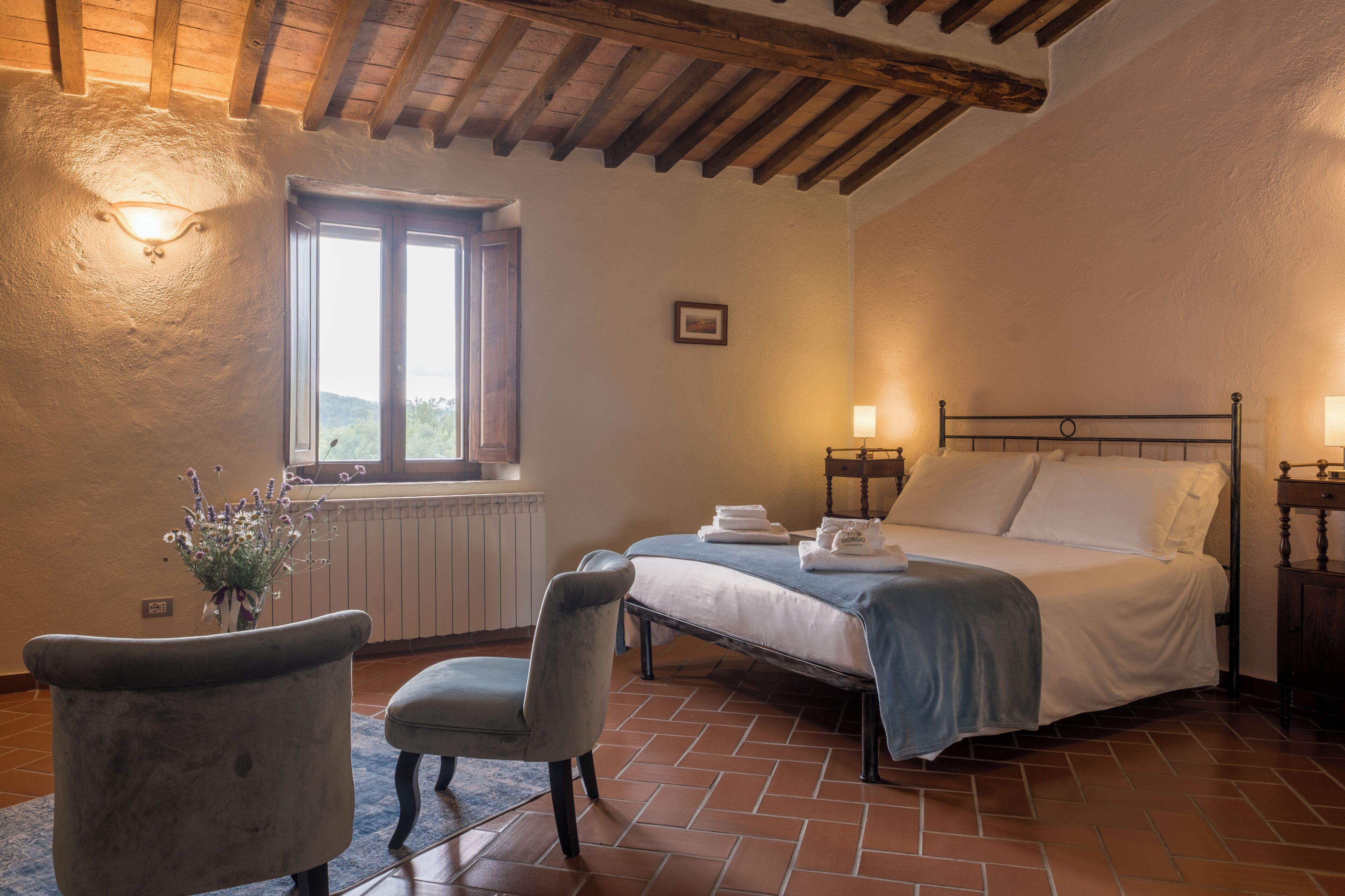 Un dormitorio con cama, una silla, una ventana y un radiador.