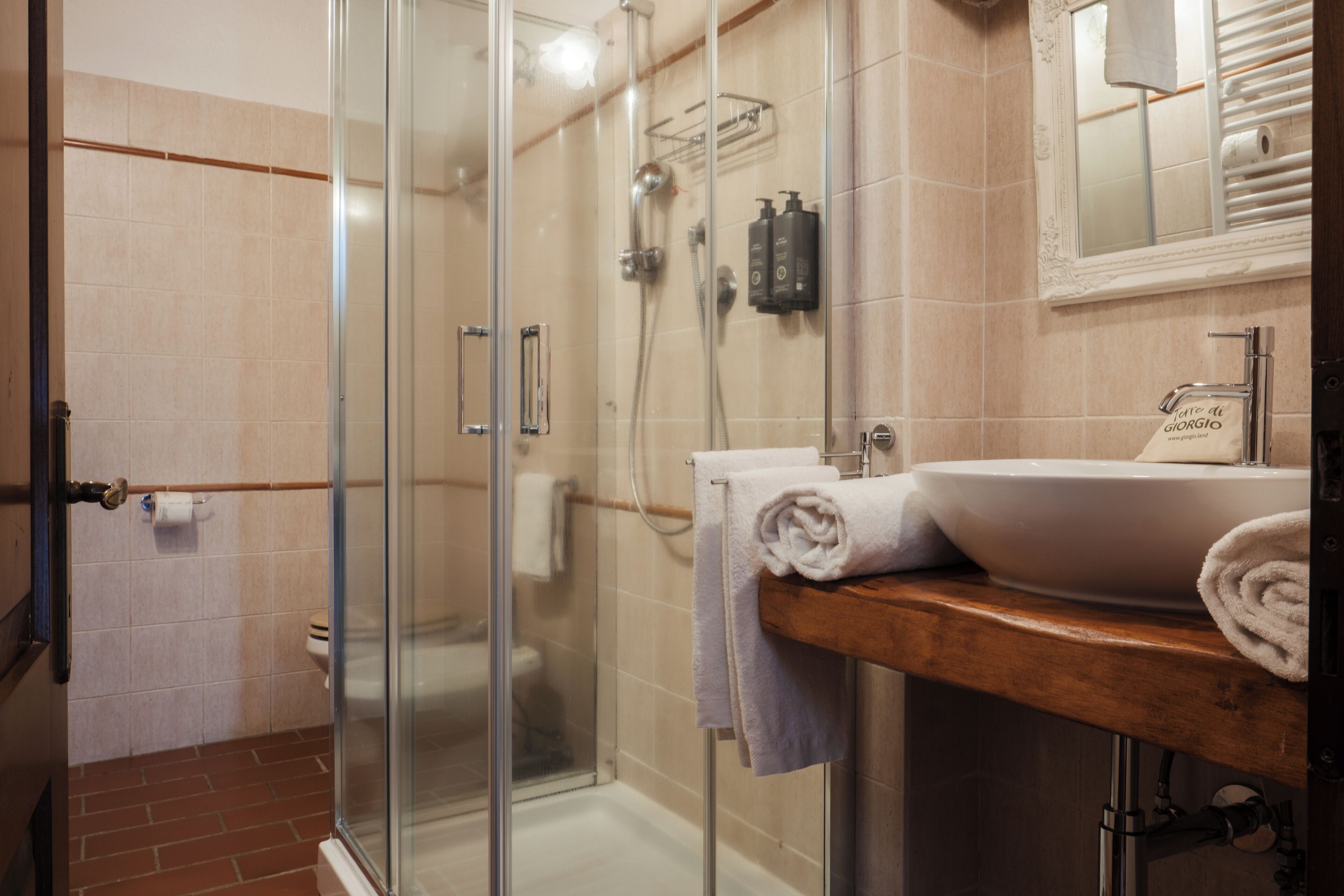 A modern bathroom with a glass shower enclosure, a wooden vanity with a sink, and a mirror above the sink.