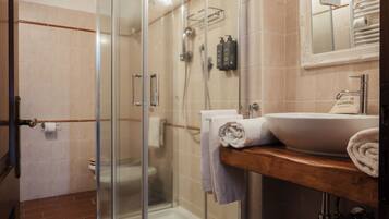 A modern bathroom with a glass shower enclosure, a wooden vanity with a sink, and a mirror above the sink.