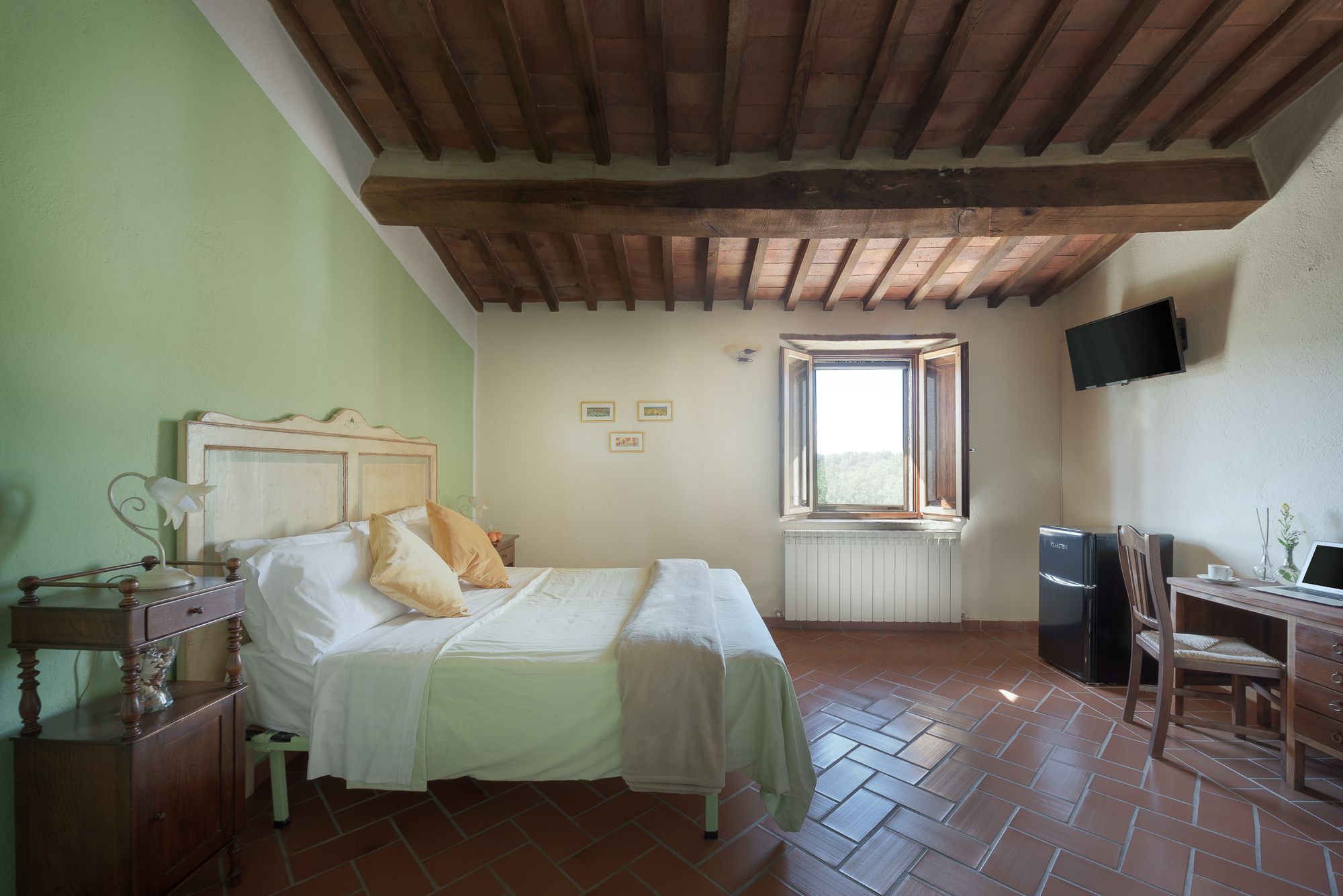 Un dormitorio con cama, mesita de noche, lámpara y ventana.