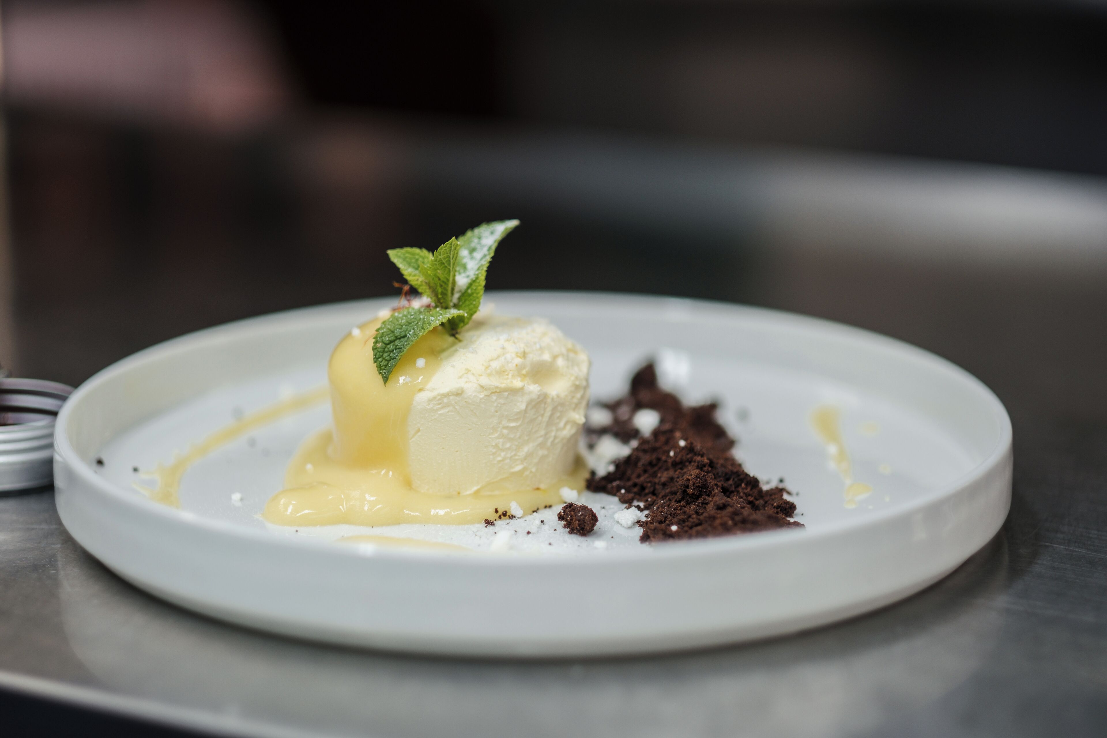 Un postre sobre un plato blanco, decorado con una hoja de menta.