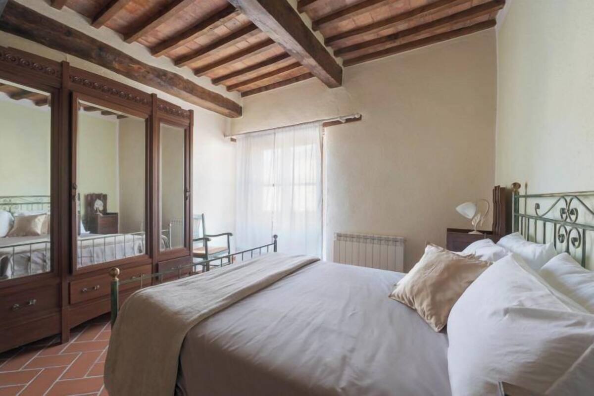Une chambre avec un grand lit, une armoire en bois et un balcon avec vue.