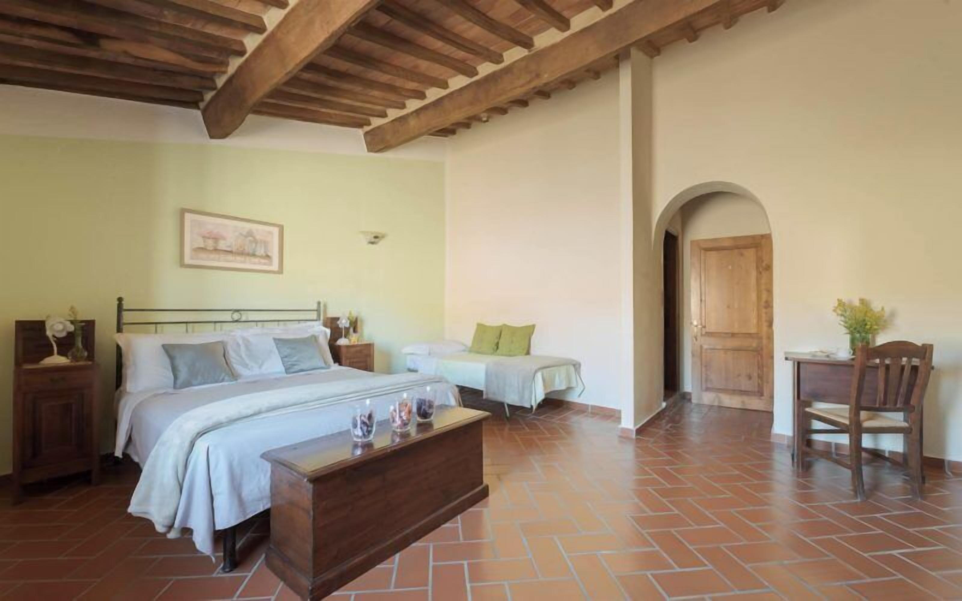 A bedroom with two beds, a wooden bench, a nightstand, and a chair.