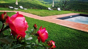 Zona de piscina con sillas de descanso y vistas a colinas verdes.