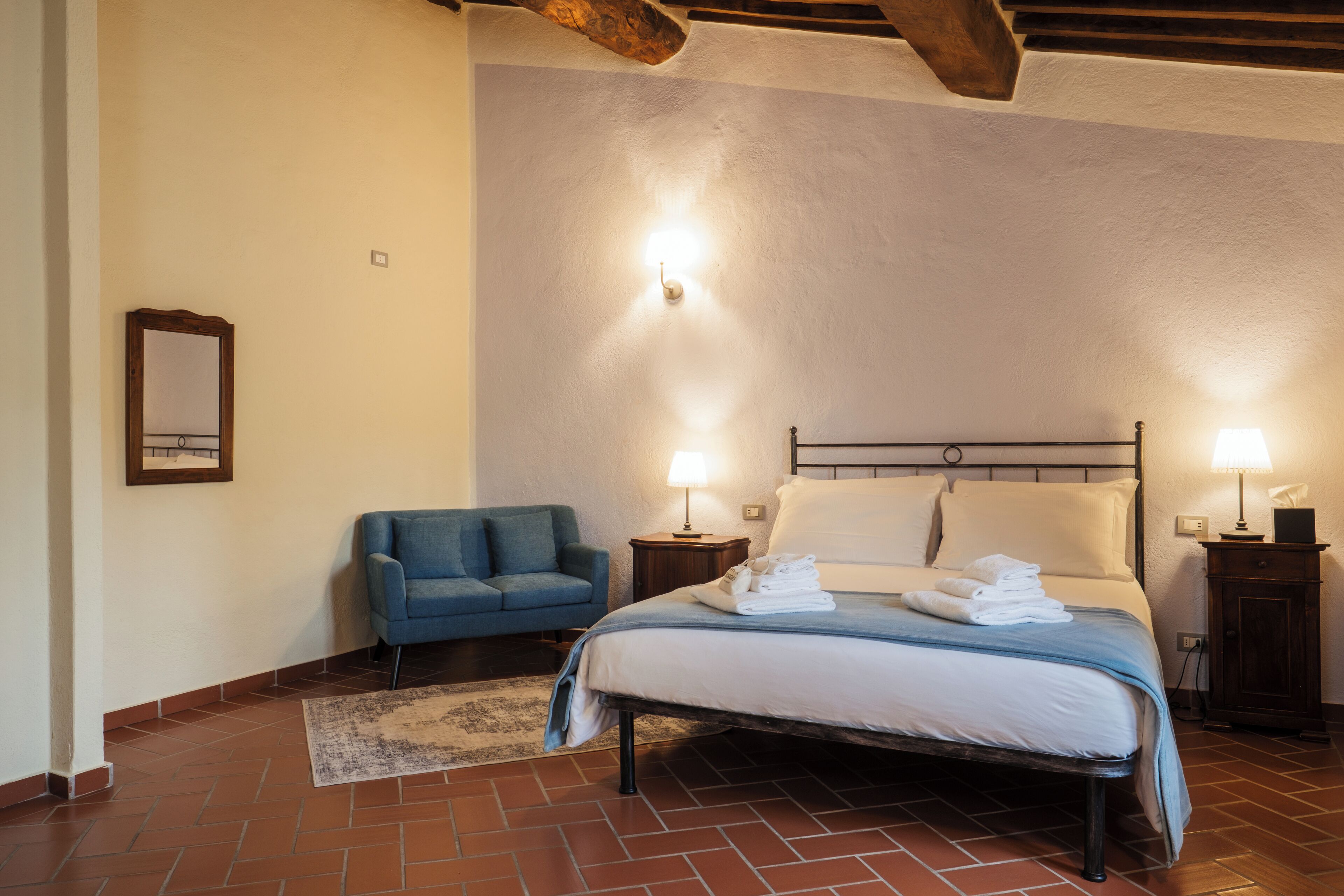 Una camera da letto con un letto, lampade da comodino, una sedia e un comodino.