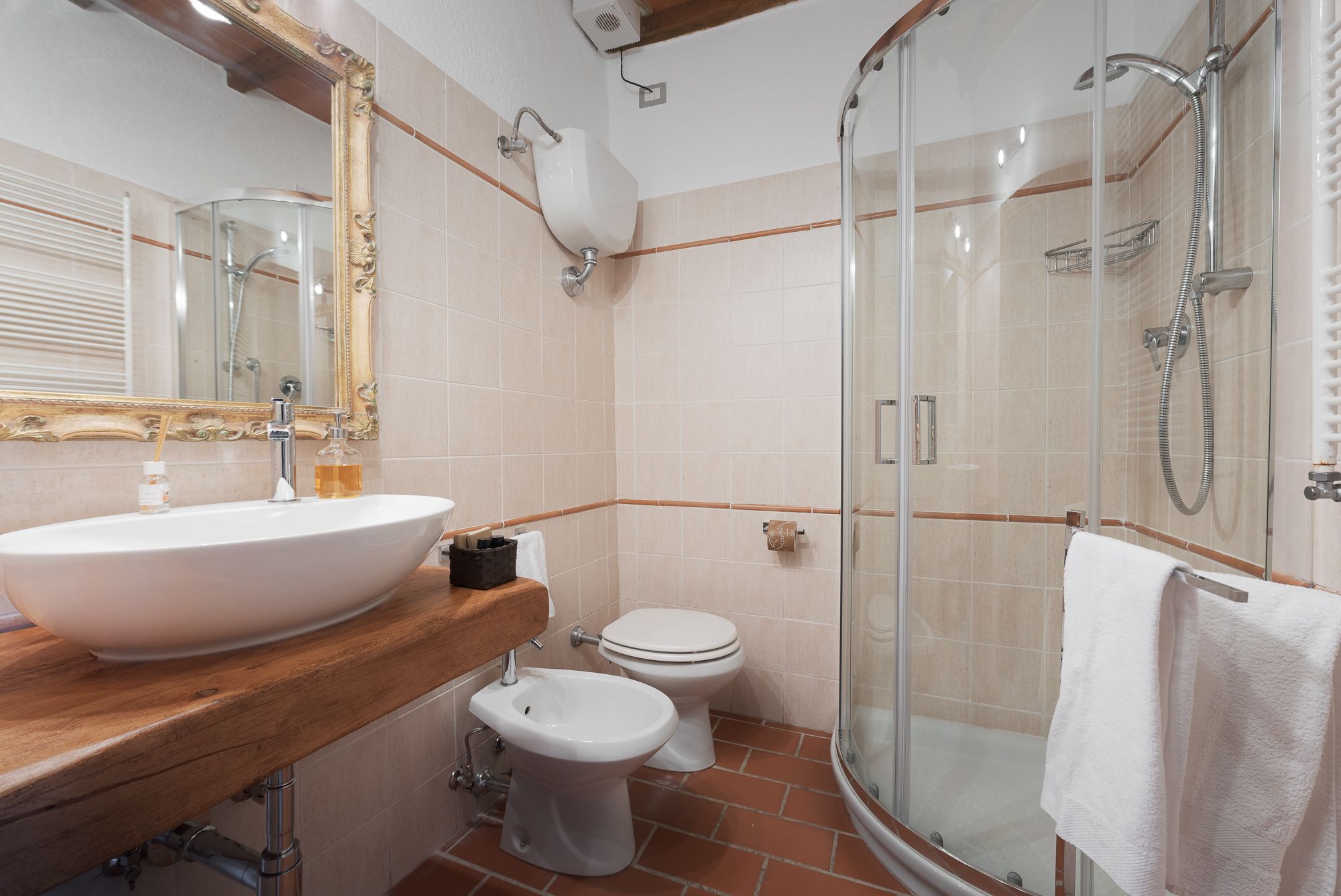 A bathroom with a large sink, toilet, and glass-enclosed shower.