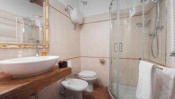 A bathroom with a large sink, toilet, and glass-enclosed shower.