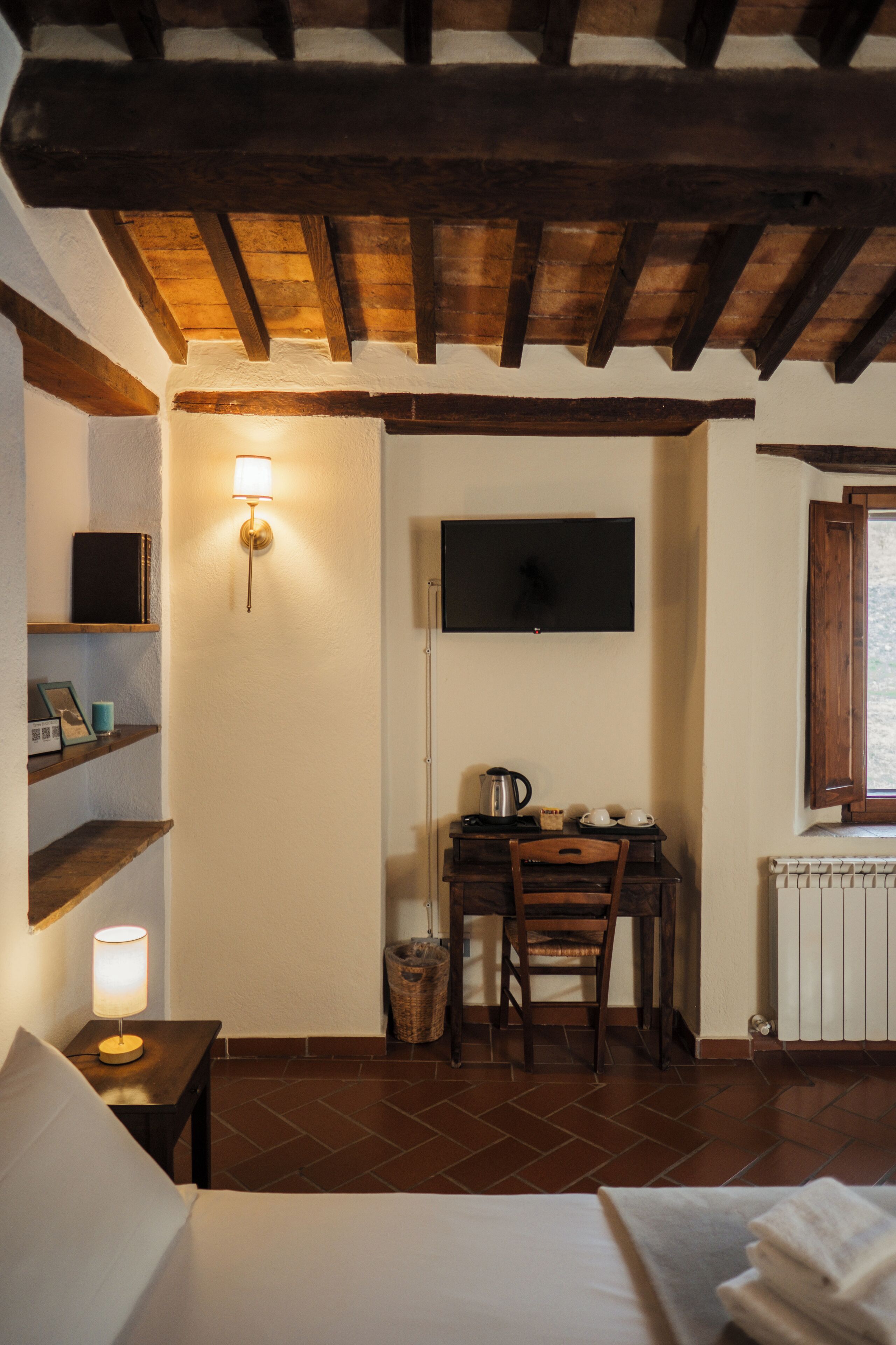 Ein gemütliches Zimmer mit einem Bett, einem Schreibtisch mit Stuhl, einem Fernseher und einem Regal mit Büchern und einer Lampe.