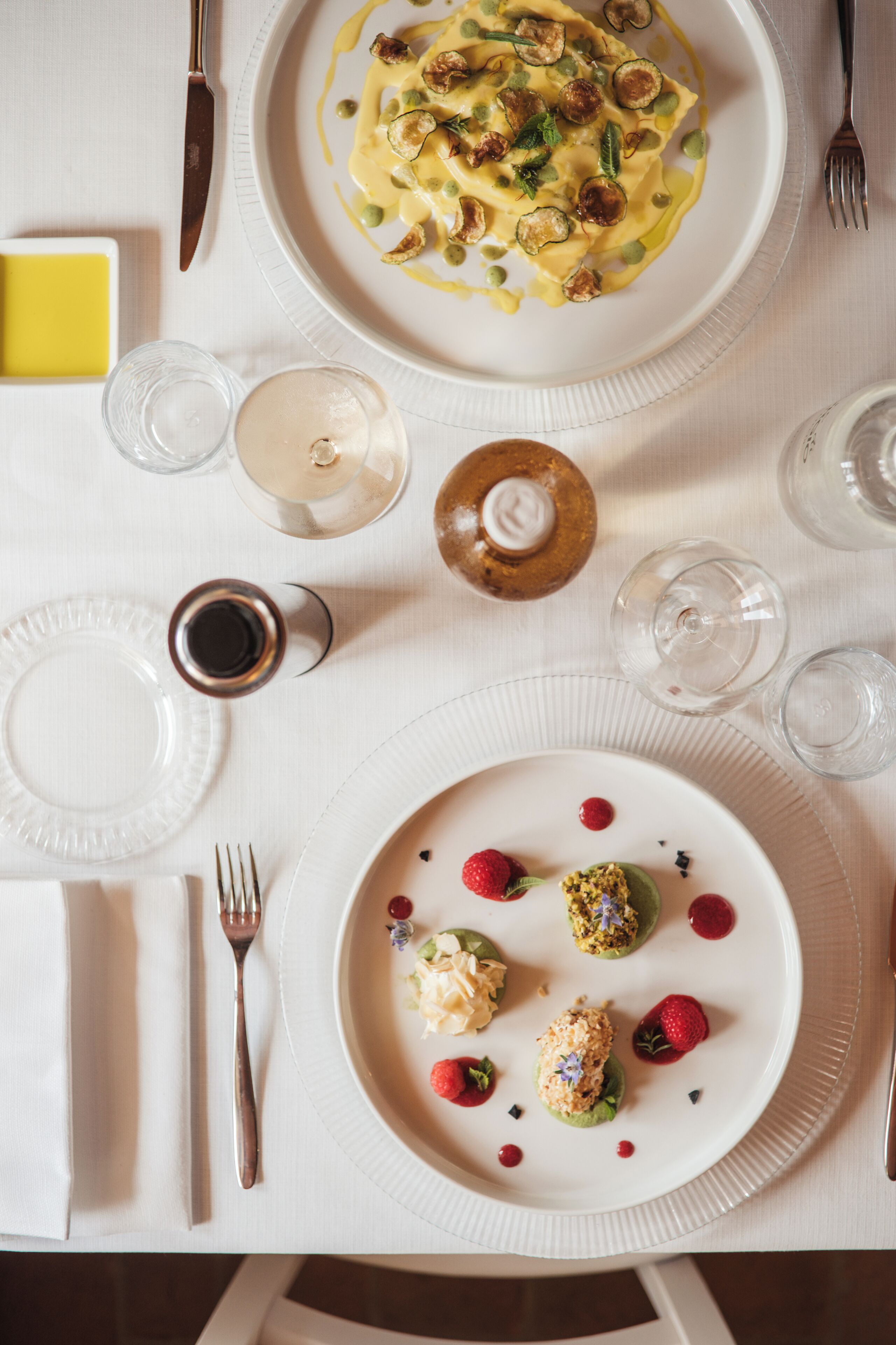 A dining table with plates of food, glasses, and cutlery.