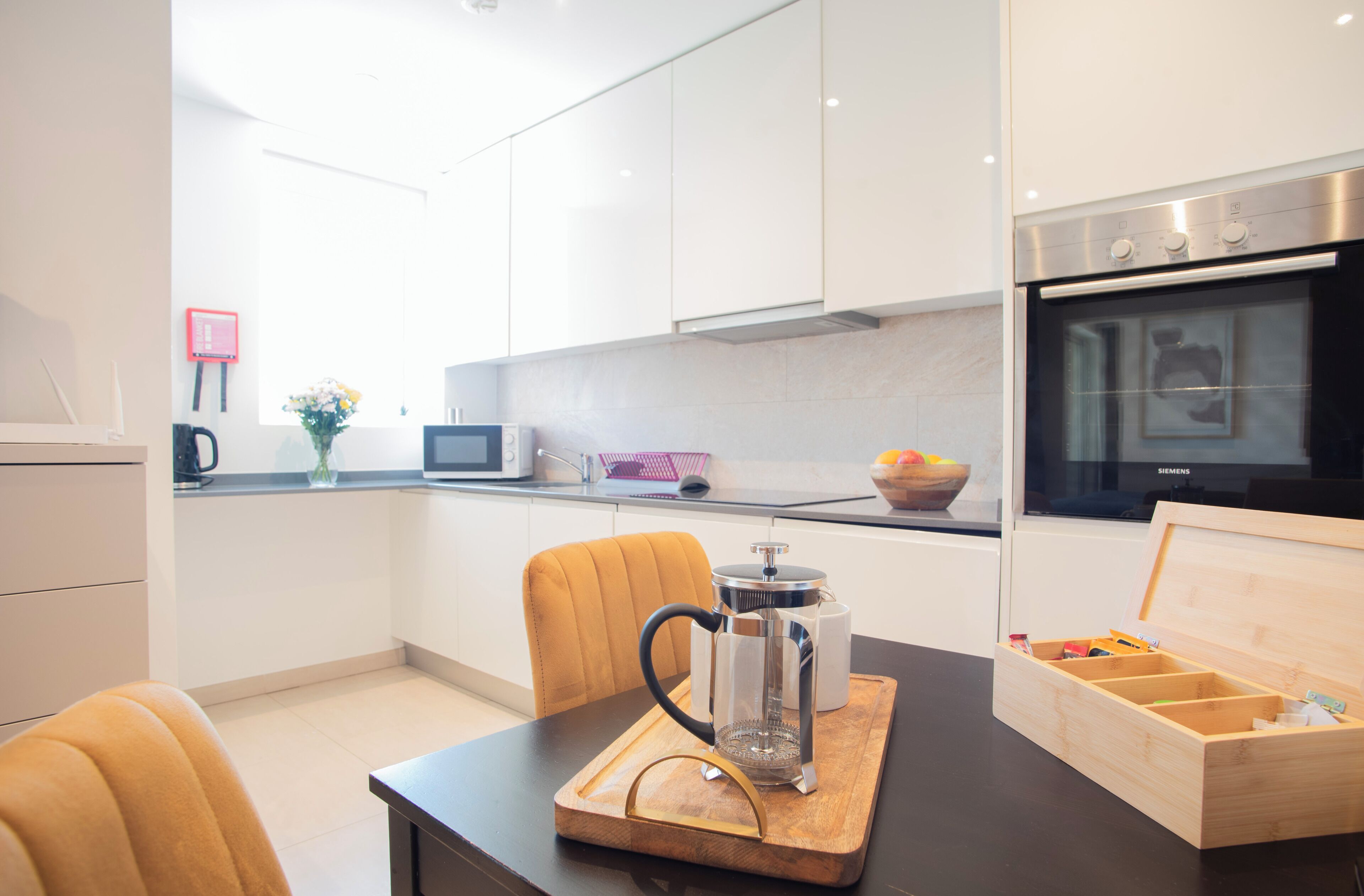 Een moderne keuken met witte kasten, een koffiezetapparaat, een magnetron en een oven.