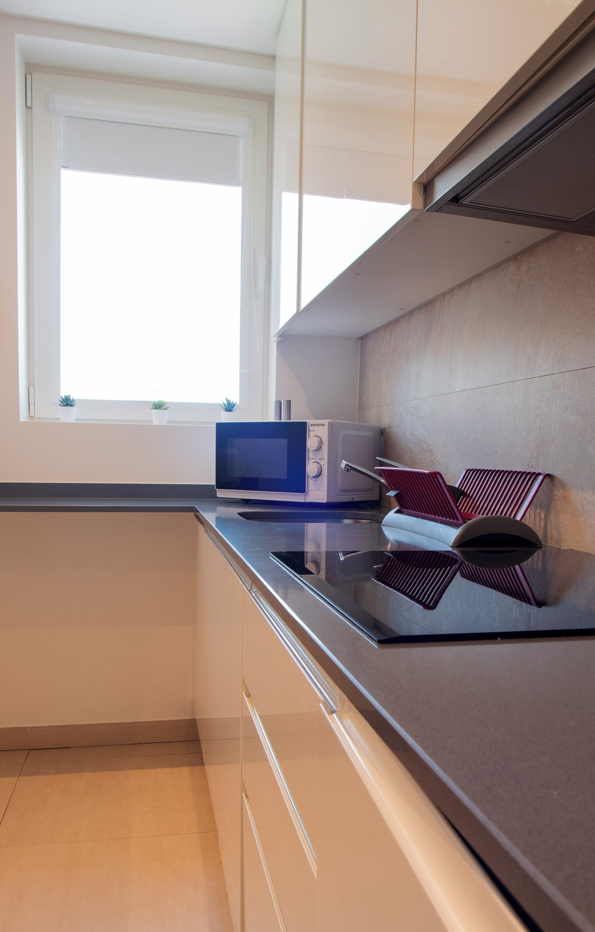 Una cucina moderna con forno a microonde, tostapane e sedie a righe rosse.