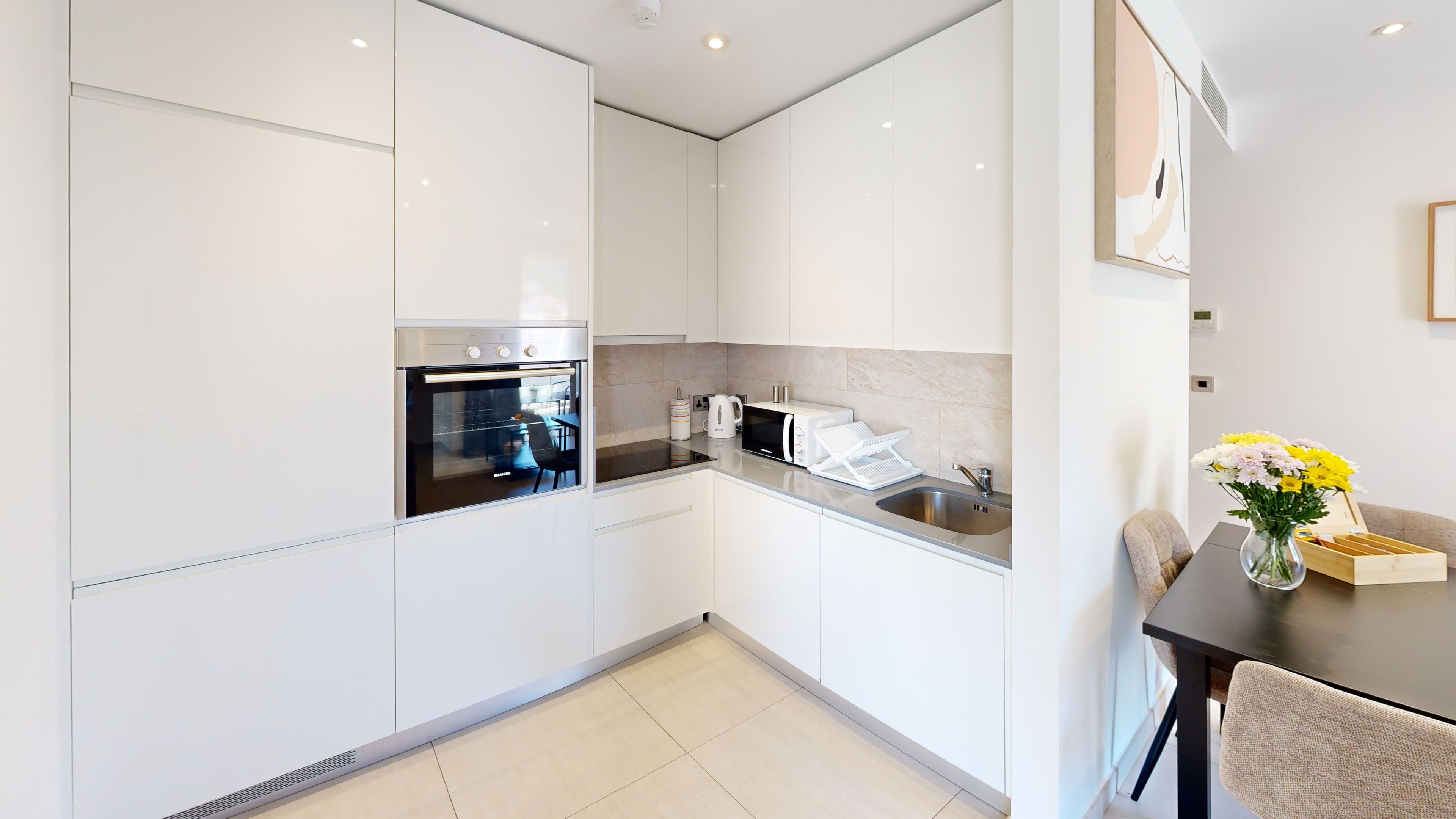 A modern kitchen with white cabinetry, stainless steel appliances, and a tiled backsplash.