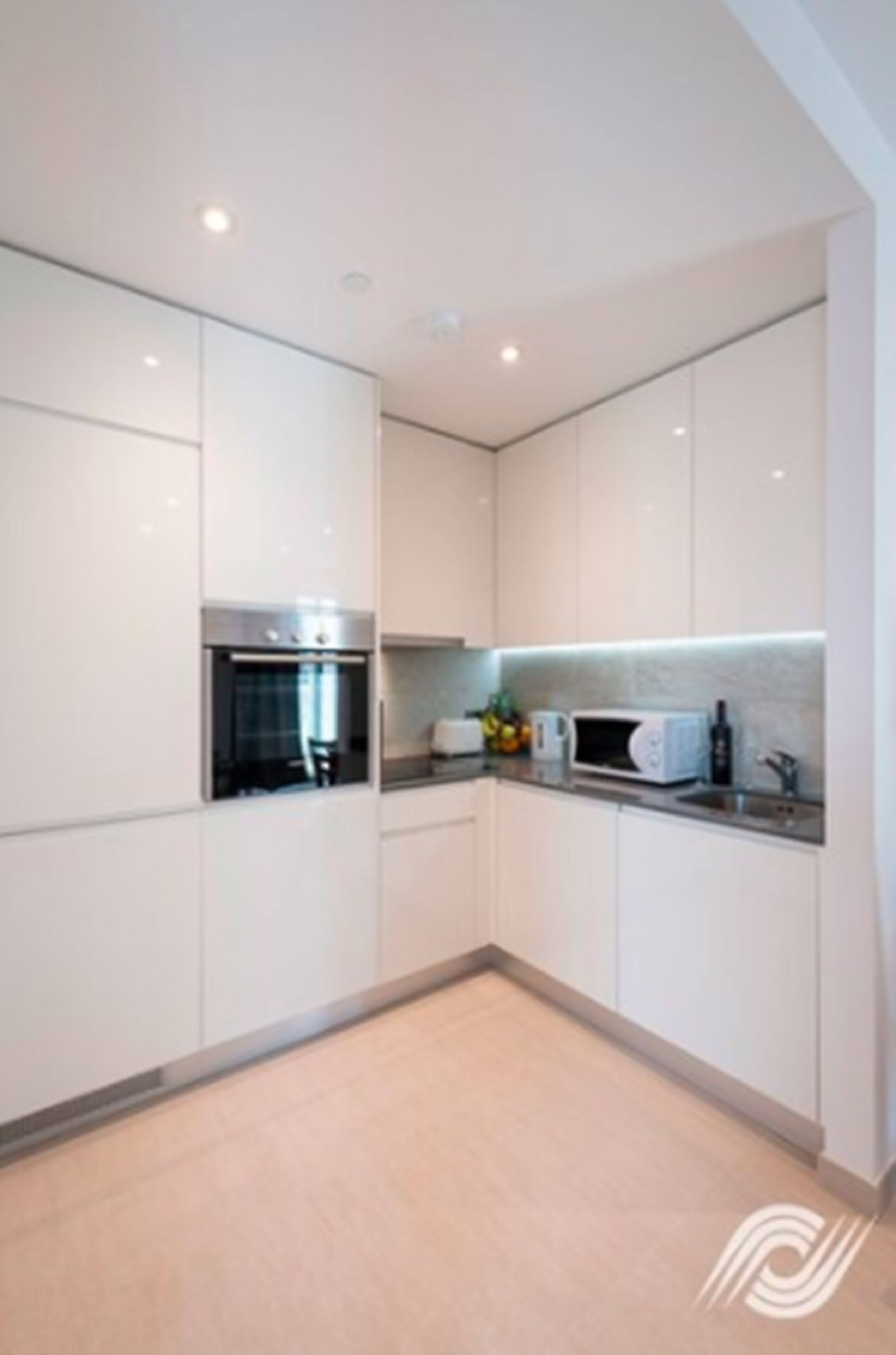 Een moderne keuken met witte kasten, een magnetron en een inbouwoven.
