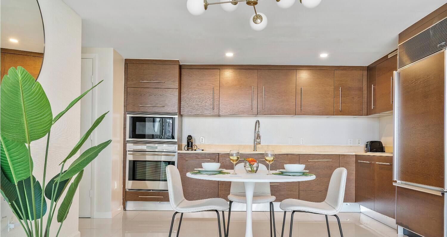A modern kitchen with wooden cabinets, a white dining table, and chairs.