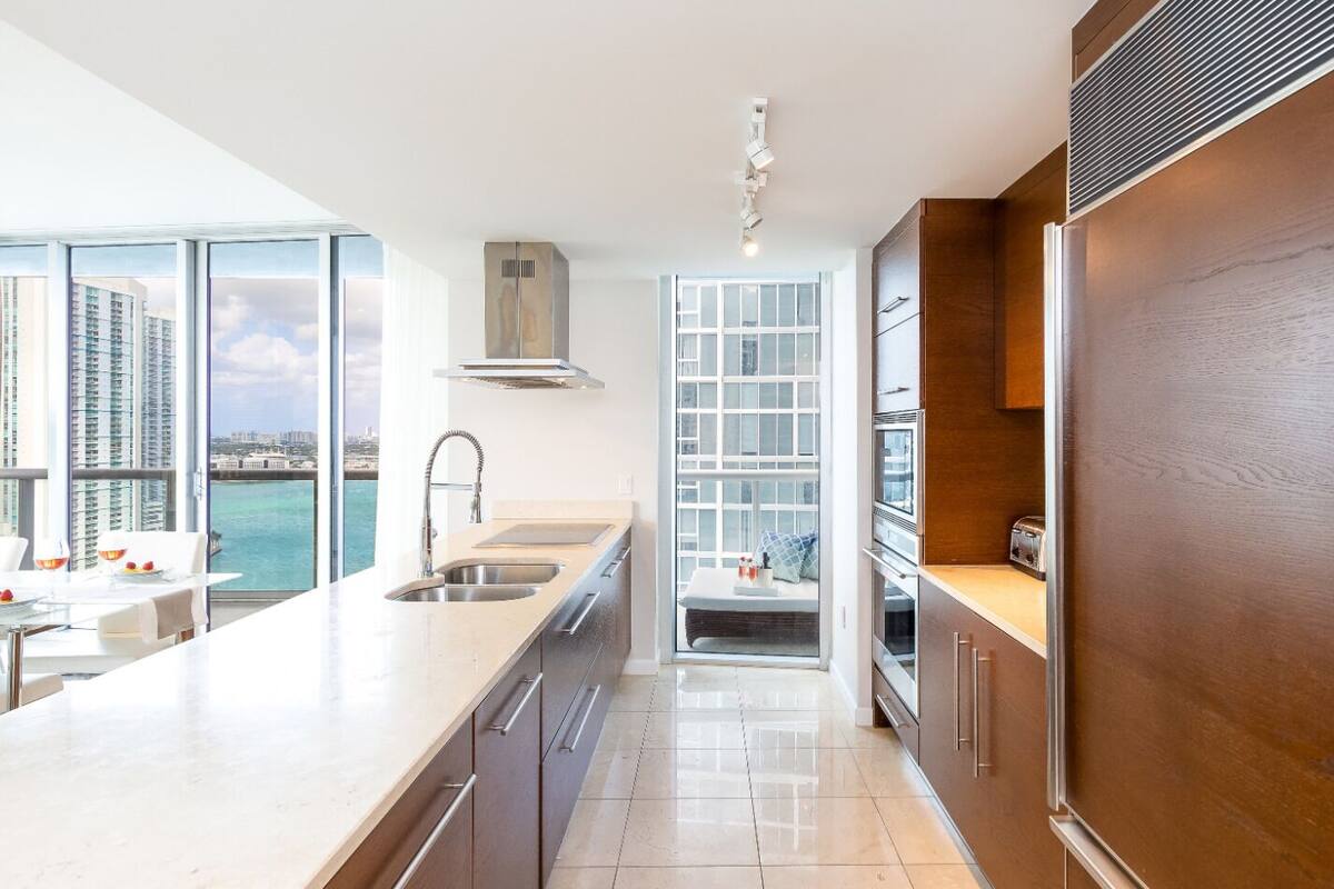 A modern kitchen with a large island, stainless steel appliances, and a view of the city.