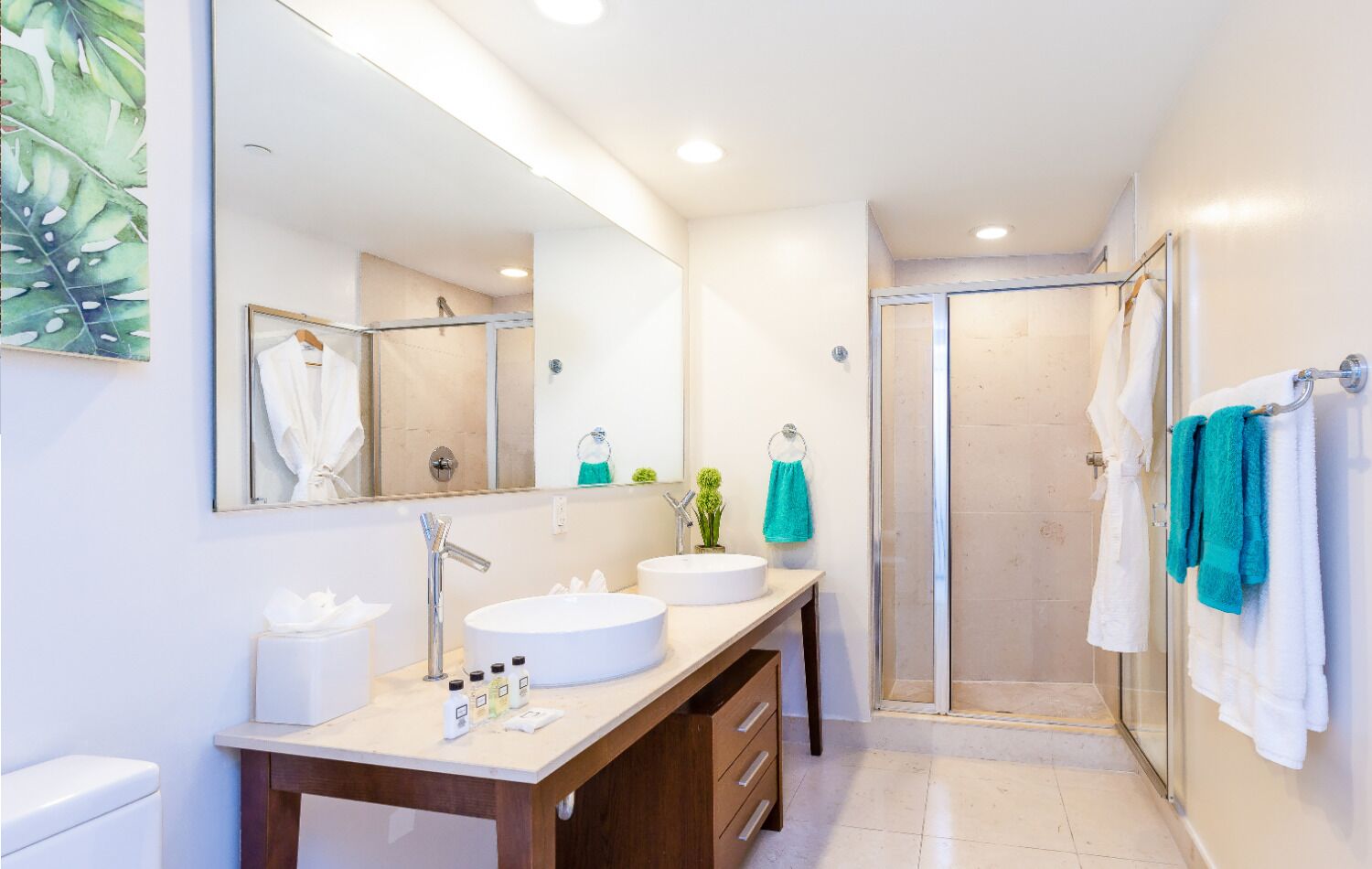 A modern bathroom with a large mirror, two sinks, a shower, and a wooden vanity.