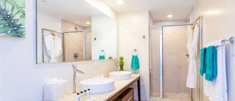 A modern bathroom with a large mirror, two sinks, a shower, and a wooden vanity.