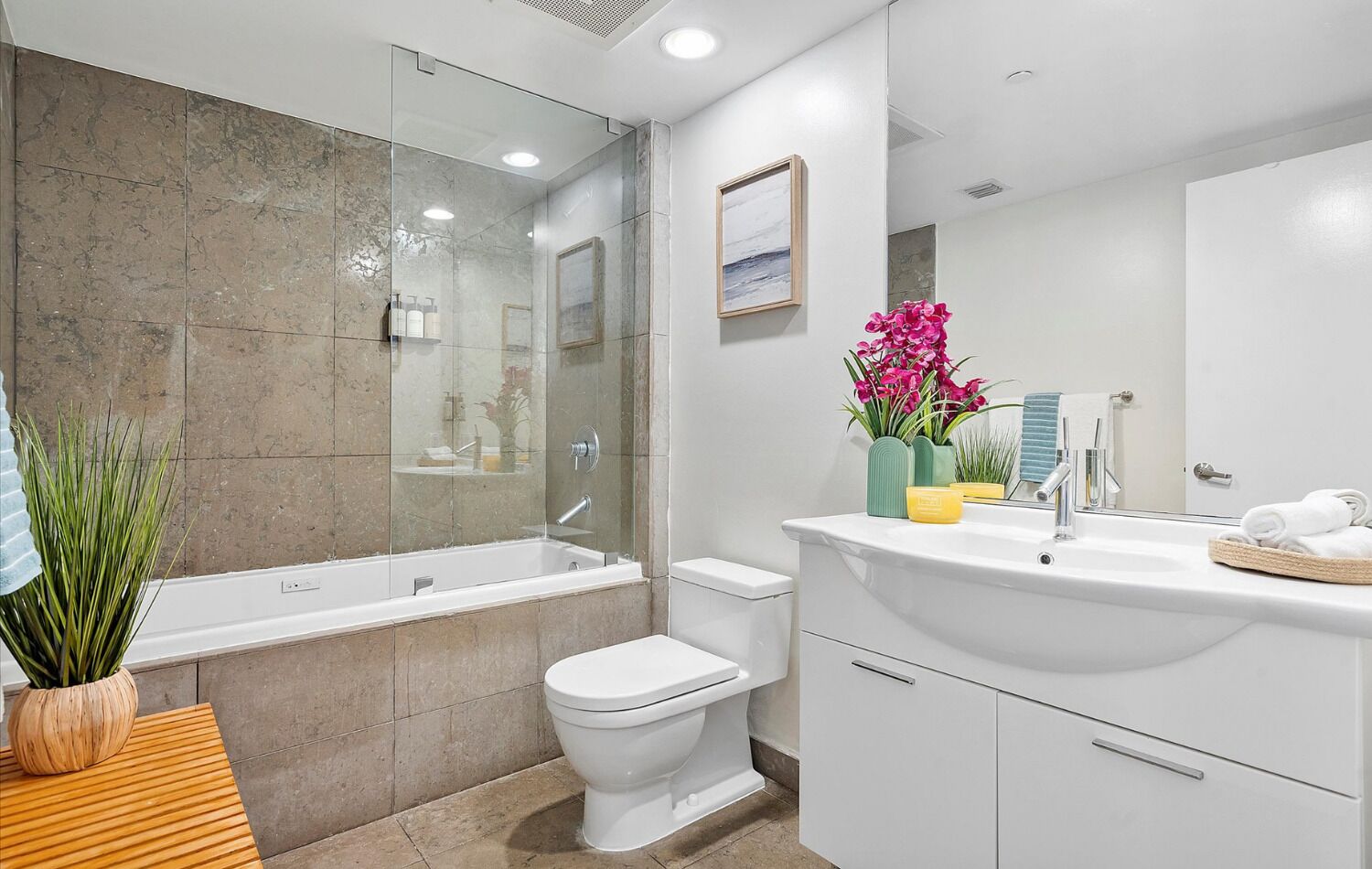 Een moderne badkamer met een douche met glazen wand, een wit toilet en een wastafelmeubel met spiegel en wastafel.