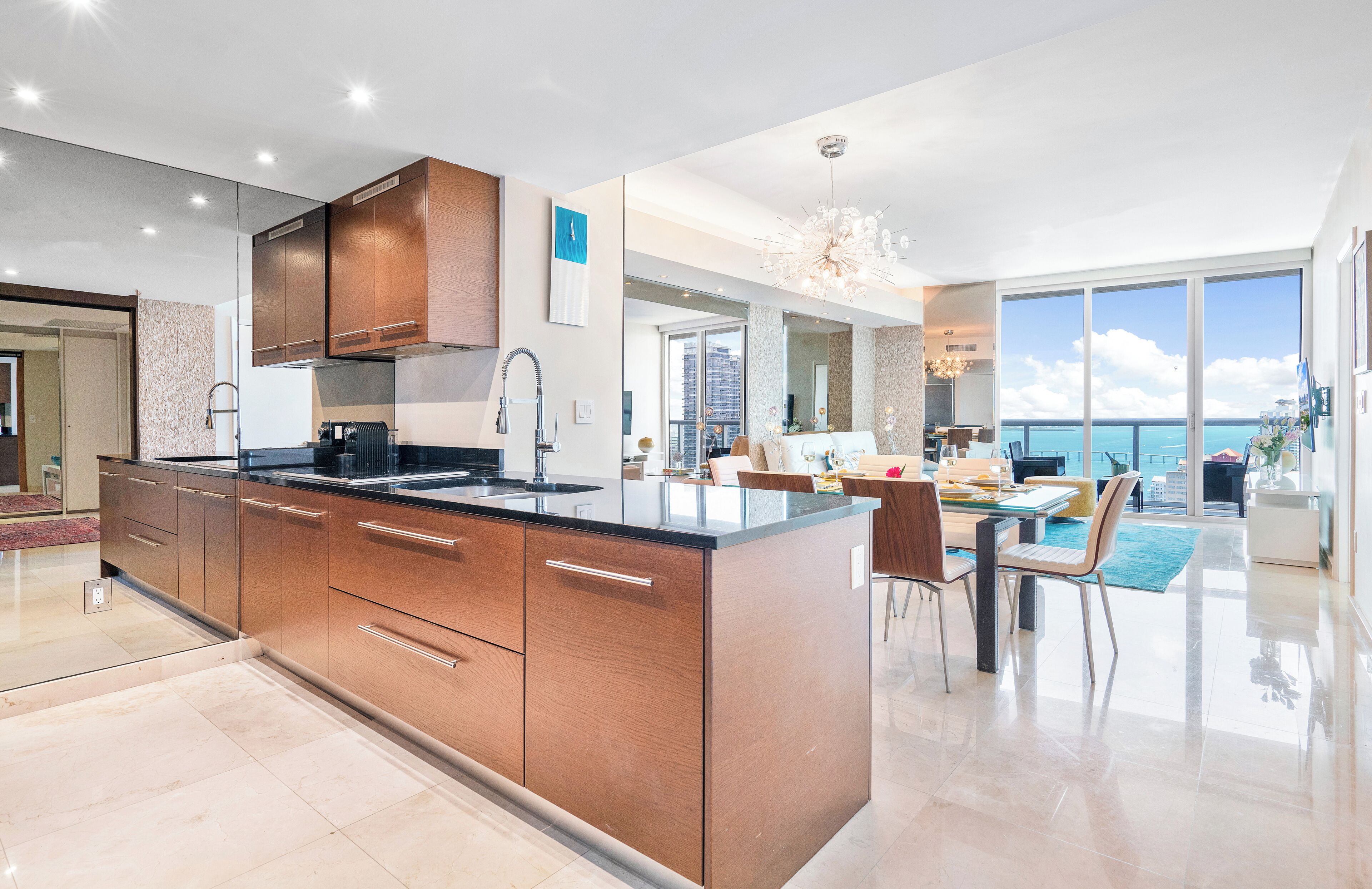 A modern kitchen with a large island, a dining area with a view, and a spacious living area with a balcony.